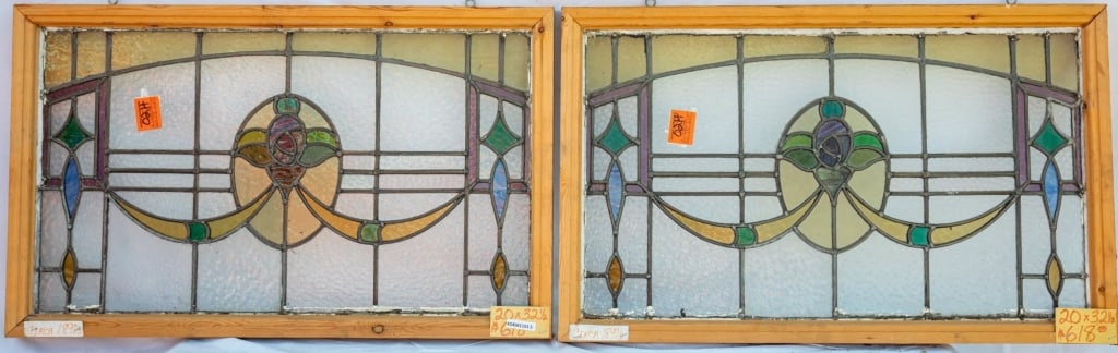 PAIR OF FRENCH ART NOUVEAU STAINED GLASS PANELS: Pair of French Art Nouveau stained glass panels with a central floral medallion, ribbon motif accents, and abstract symmetrical details. Approximate dimensions: h. 20", w. 32.5" Disclaimer: This is an