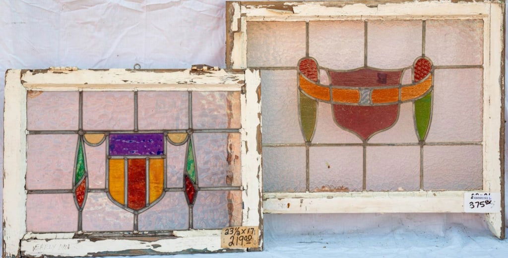 TWO CONTINENTAL STAINED GLASS PANELS: Two Continental stained glass panels, both with shield-shaped central medallions and ribbon accents. Approximate dimensions: h. 25", w. 31" Disclaimer: This is an online court ordered bankruptcy sale.