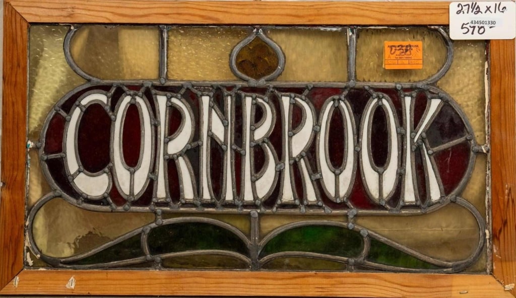 ENGLISH 'CORNBROOK' STAINED GLASS PANEL: English 'Cornbrook' stained glass panel with chartreuse, emerald green, and red accents, inscribed "Cornbrook". Approximate dimensions: h. 16", w. 27.5" Disclaimer: This is an online court ordered ban