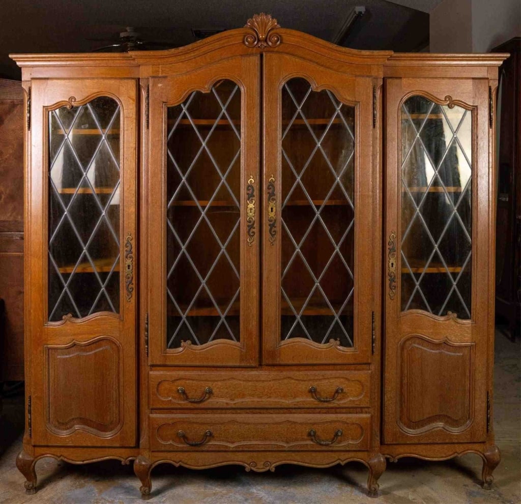 FRENCH OAK STAINED GLASS BOOKCASE: French oak stained glass bookcase with shell-carved crest and yellow stained glass. Approximate dimensions: h. 82", w. 49.5", d. 17.5" Disclaimer: This is an online court ordered bankruptcy sale. Part