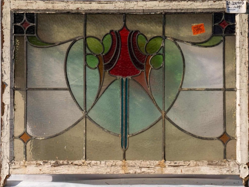 FRENCH ART NOUVEAU STAINED GLASS PANEL: French Art Nouveau stained glass panel with a heart-shaped floral motif central medallion and purple, red, and amber accents at the corners. Approximate dimensions: h. 28", w. 42" Disclaimer: This is