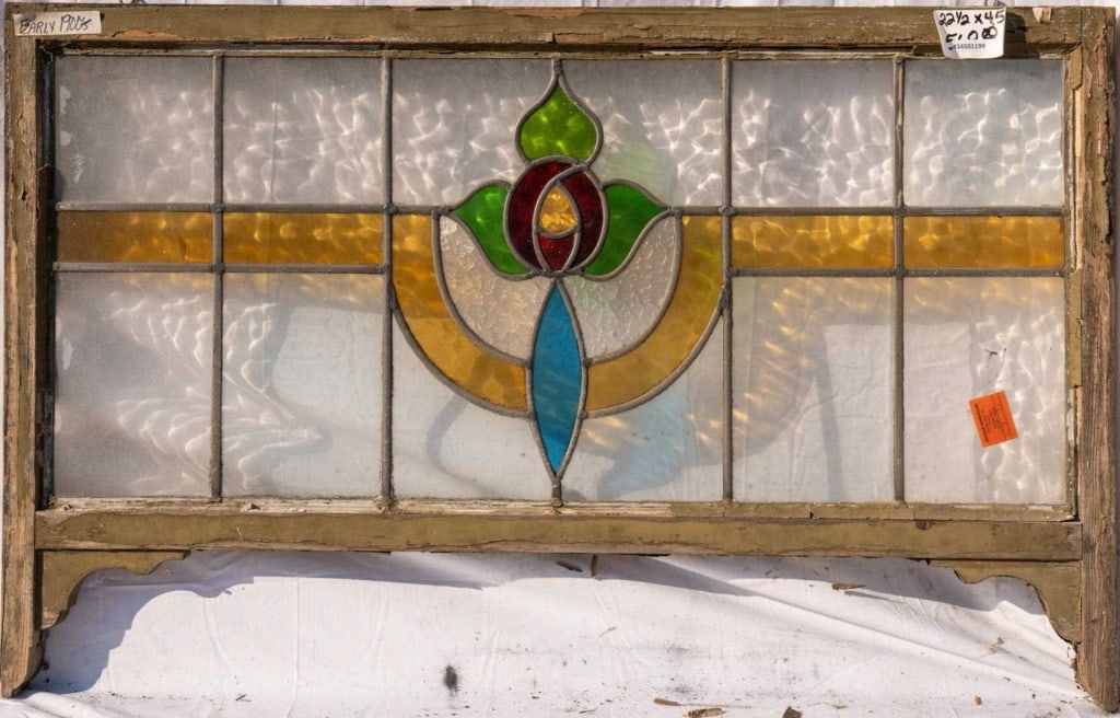 FRENCH ART NOUVEAU STAINED GLASS PANEL: French Art Nouveau stained glass panel with a rose and leaf medallion, accented with amber and blue stained glass panels. Approximate dimensions: h. 22.5", w. 35" Disclaimer: This is an online court o