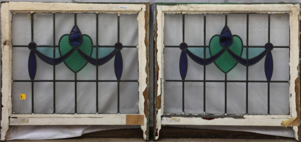 PAIR OF ENGLISH ART NOUVEAU STAINED GLASS PANELS: Pair of English Art Nouveau stained glass panels with heart-shaped green medallion, blue drop wispy glass detail, and blue garland motif. Approximate dimensions: h. 27", w. 28" Disclaimer: This is an