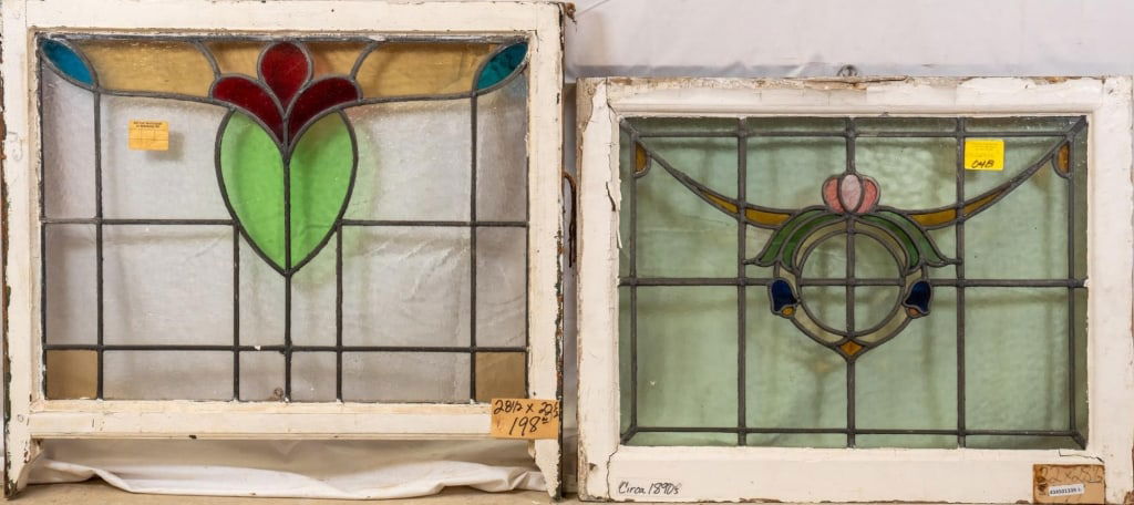 TWO FRENCH STAINED GLASS PANELS: Two French stained glass panels, one with a floral wreath-shaped medallion and garland accents, and the other with a green and red heart-shaped medallion. Approximate dimensions: h. 22.5", w. 28.5" Di