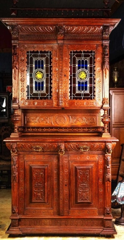 FRENCH RENAISSANCE REVIVAL STAINED GLASS BUFFET: French Renaissance Revival stained glass buffet with carved backsplash, figural supports, lion head and brass ring decorations, carved gallery, and finials. Approximate dimensions: h. 102", w. 47", d.