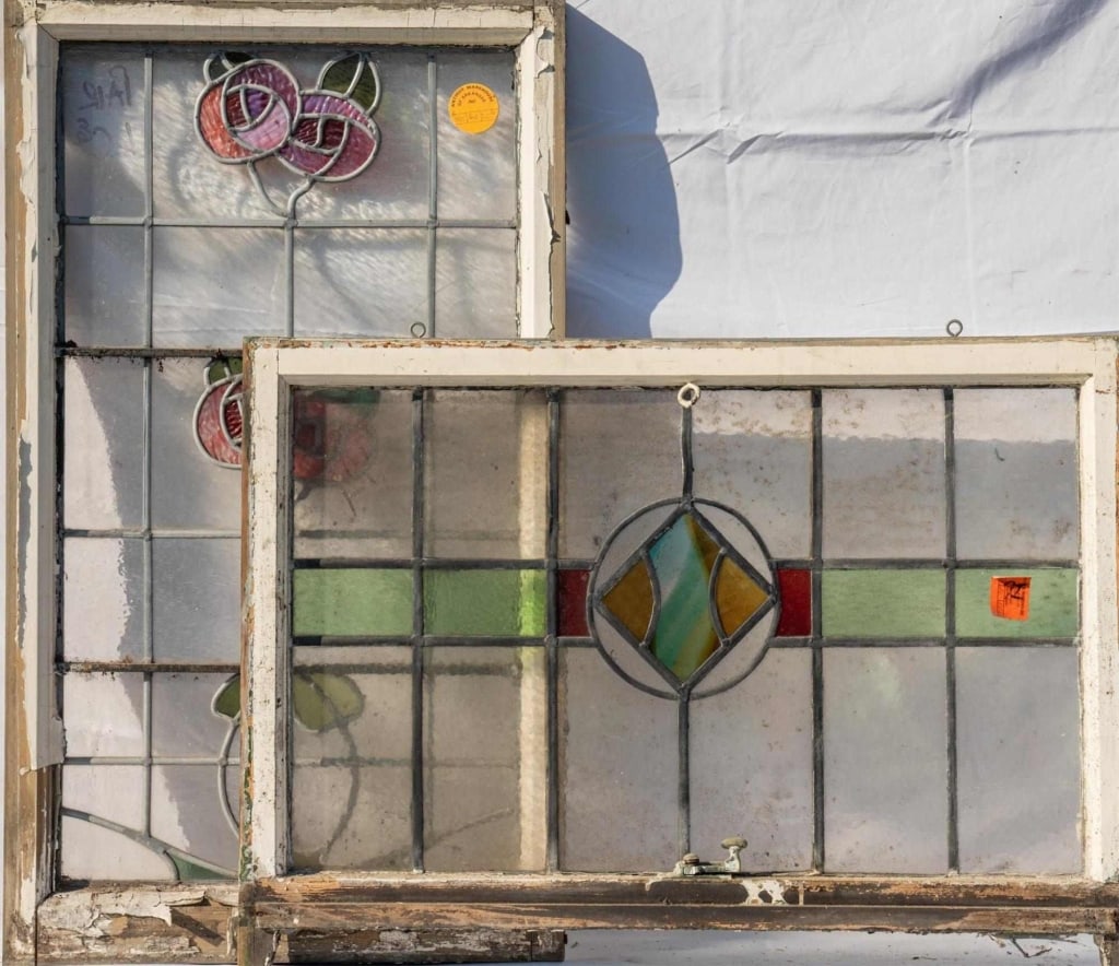 TWO FRENCH STAINED GLASS PANELS: Two French stained glass panels, one with a floral motif in wispy and textured glass, and the other with a rhombic medallion with wispy glass. Approximate dimensions: h. 23", w. 34.5" Disclaimer: This