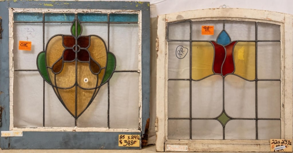 TWO FRENCH ART NOUVEAU STAINED GLASS PANELS: Two French Art Nouveau stained glass panels, one with a heart-shaped red flower with leaves and amber accents, and the other with a blue and red tulip medallion. Approximate dimensions: h. 24.5", w. 2