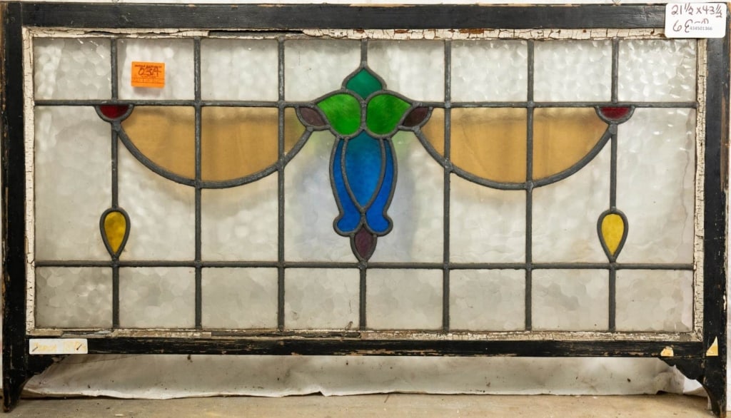 FRENCH ART NOUVEAU STAINED GLASS PANEL: French Art Nouveau stained glass panel with blue tulip-shaped medallion, and red, canary yellow, and amber stained glass accents. Approximate dimensions: h. 21.5", w. 43.5" Disclaimer: This is an onli