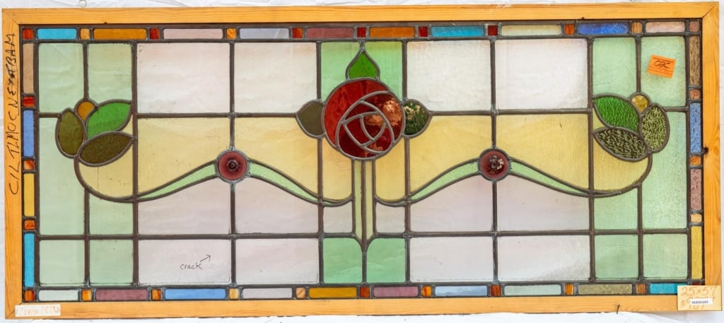 FRENCH ART NOUVEAU JEWELED STAINED GLASS PANEL: French Art Nouveau jeweled stained glass panel with a central rose and leaf medallion, two red jeweled accents, and multicolored leaded stained glass panels. Approximate dimensions: h. 25", w. 57" Dis