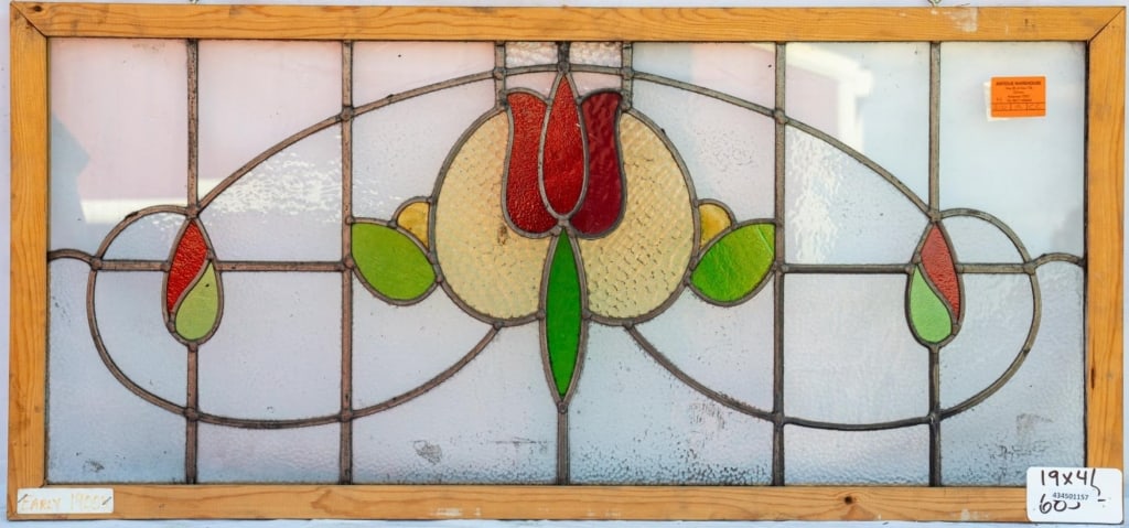 FRENCH ART NOUVEAU STAINED GLASS PANEL: French Art Nouveau stained glass panel with a red tulip medallion, flanked by leaves and green and red drop elements. Approximate dimensions: h. 19", w. 41" Disclaimer: This is an online court ordered