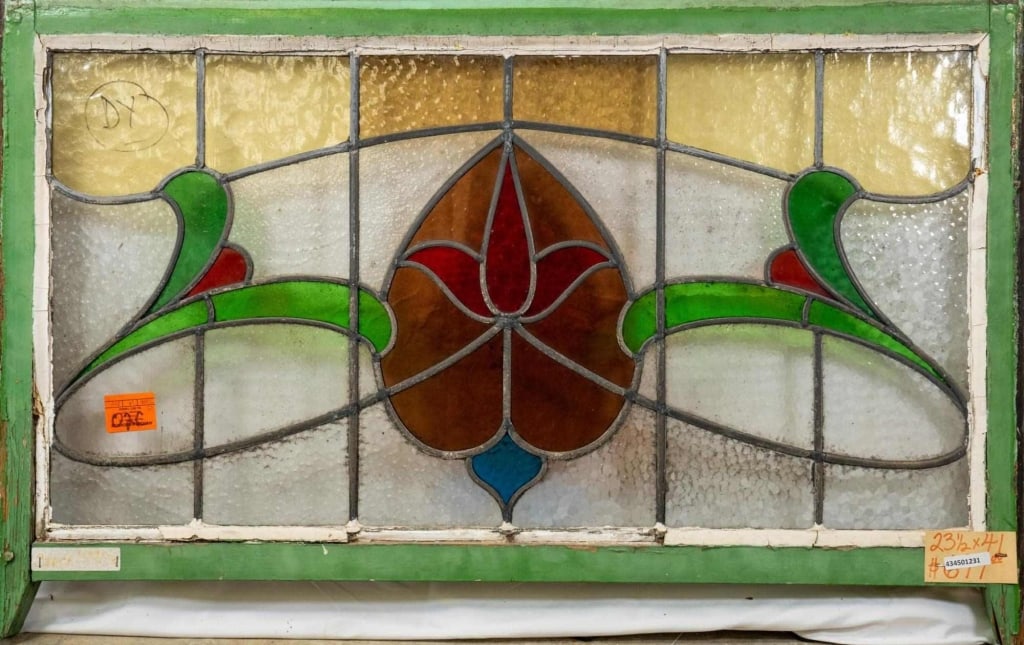 FRENCH ART NOUVEAU STAINED GLASS PANEL: French Art Nouveau stained glass panel with a heart-shaped floral medallion and green and red floral side accents. Approximate dimensions: h. 23.5", w. 41" Disclaimer: This is an online court ordered
