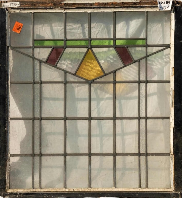 ENGLISH ART DECO STAINED GLASS PANEL: English Art Deco stained glass panel with a geometric medallion in red, amber, and green. Approximate dimensions: h. 39", w. 36" Disclaimer: This is an online court ordered bankruptcy sale. Participat