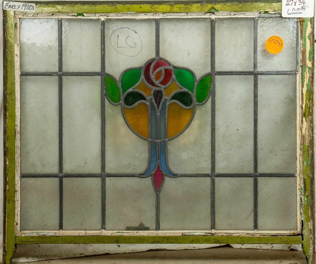 CONTINENTAL STAINED GLASS PANEL: Continental stained glass panel with rose and leaf medallion, amber and blue accents, and colorless leaded glass panels. Approximate dimensions: h. 27", w. 34" Disclaimer: This is an online court orde