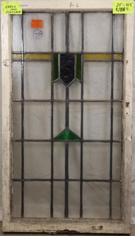 SCOTTISH ART DECO STAINED GLASS PANEL: Scottish Art Deco stained glass panel with geometric medallion and dark blue and green wispy glass details. Approximate dimensions: h. 42.5", w. 24" Disclaimer: This is an online court ordered bankrup