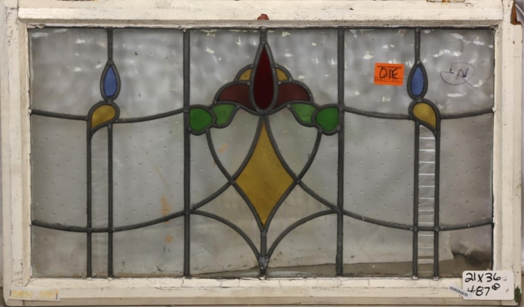 ANTIQUE ENGLISH STAINED GLASS PANEL: Antique English stained glass panel with floral medallion and canary yellow and blue leaf-shaped accents to the sides. Approximate dimensions: h. 21", w. 36" Disclaimer: This is an online court ordere
