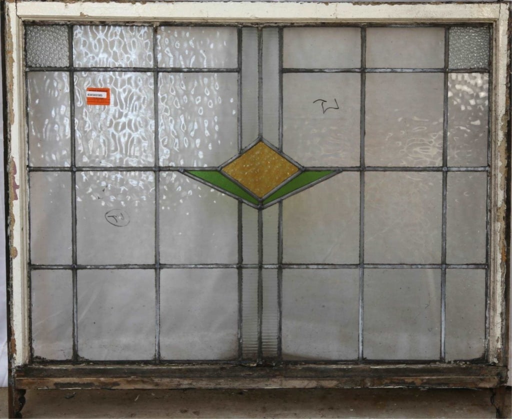 ENGLISH ART DECO STAINED GLASS PANEL: English Art Deco stained glass panel with a green and yellow geometric medallion and textured colorless leaded glass panels. Approximate dimensions: h. 38.5", w. 44.5" Disclaimer: This is an online co