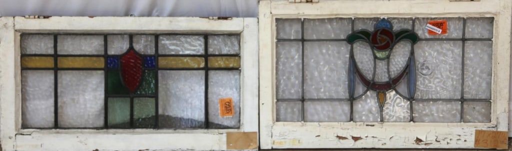 TWO ANTIQUE CONTINENTAL STAINED GLASS PANELS: Two antique Continental stained glass panels, one with a floral medallion and garland motif with colorless leaded glass panels, another with a red shield medallion with blue, amber, and green details.