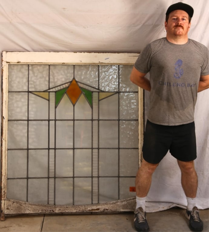 ENGLISH ART DECO STAINED GLASS PANEL: English Art Deco stained glass panel with a medallion, amber rhombic central element, green and yellow accents, and textured colorless leaded glass panels. Approximate dimensions: h. 52", w. 45" Discl