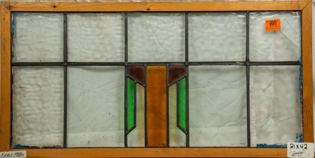 ENGLISH ART DECO STAINED GLASS PANEL: English Art Deco stained glass panel with red, amber, and green geometric medallion. Approximate dimensions: h. 21", w. 42" Disclaimer: This is an online court ordered bankruptcy sale. Participating b