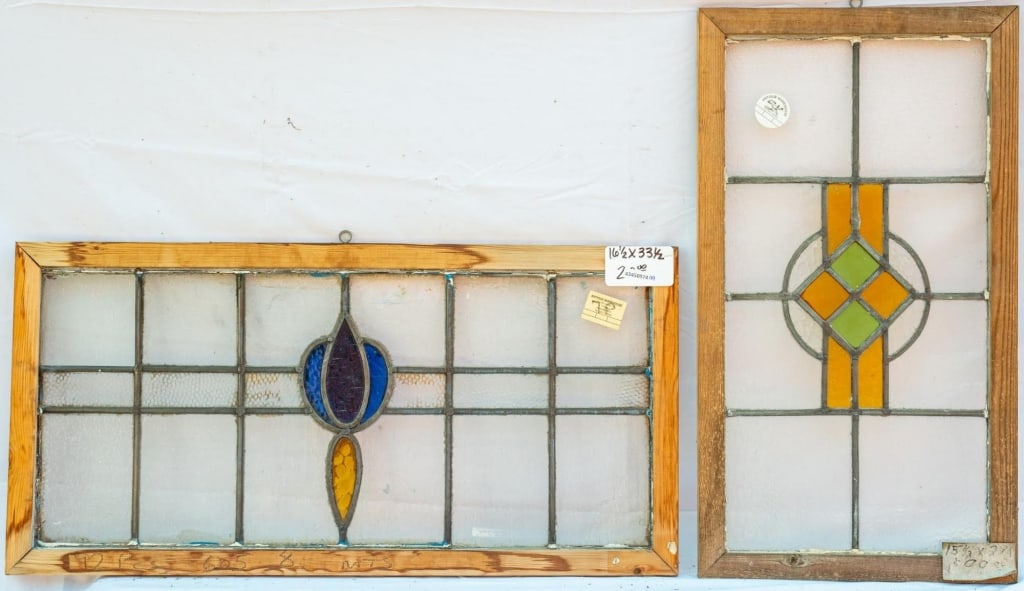 TWO CONTINENTAL STAINED GLASS PANELS: Two Continental stained glass panels with colorless leaded glass panels accented with green, amber, and purple stained glass elements. Approximate dimensions: h. 16.5", w. 33.5" Disclaimer: This is an