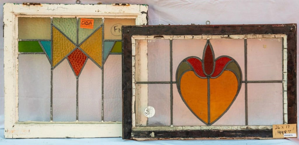 TWO FRENCH ART NOUVEAU STAINED GLASS PANELS: Two French Art Nouveau stained glass panels with green, red, and amber stained glass accents set within colorless leaded glass panels. Approximate dimensions: h. 17", w. 26" Disclaimer: This is an onl
