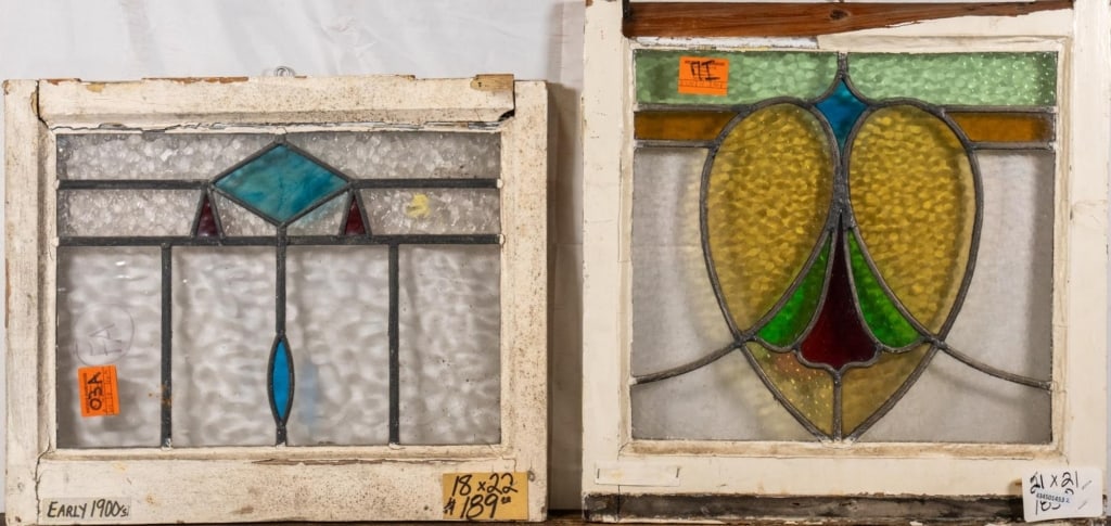 TWO CONTINENTAL STAINED GLASS PANELS: Two Continental stained glass panels, one with a blue geometric medallion and wispy glass detail, the other with a heart-shaped medallion. Approximate dimensions: h. 21", w. 21" Disclaimer: This is an