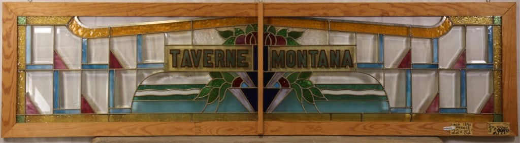 ANTIQUE 'TAVERNE MONTANA' STAINED GLASS PANEL: Antique “Taverne Montana” stained glass panel with beveled insets, textured elements, floral motif, inscribed “Taverne Montana.” Approximate dimensions: h. 22", w. 82" Disclaimer: This