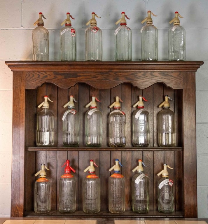 18 ENGLISH PUB SELTZER GLASS BOTTLES: Eighteen English pub seltzer glass bottles. Disclaimer: This is an online court ordered bankruptcy sale. Participating bidders must have a credit card on file with Live Auctioneers. Credit cards will 