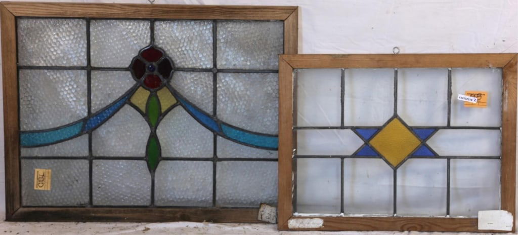TWO CONTINENTAL STAINED GLASS PANELS: Two Continental stained glass panels, one with a floral medallion featuring jeweled detail and a blue ribbon motif, and the other with a geometric medallion in blue and yellow. Approximate dimensions:
