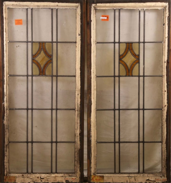 PAIR OF ANTIQUE IRISH STAINED GLASS PANELS: Pair of antique Irish stained glass panels with amber and canary yellow medallions set within colorless leaded glass. Approximate dimensions: h. 52", w. 24" Disclaimer: This is an online court ordered