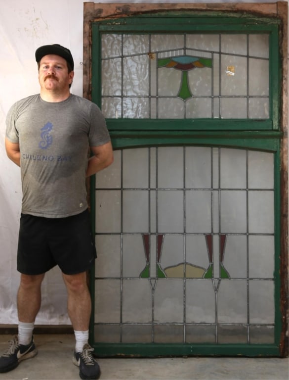 ENGLISH ART DECO STAINED GLASS PANEL: English Art Deco stained glass panel with geometric medallion in red, blue, green, and canary yellow elements, and textured colorless leaded glass panels. Approximate dimensions: h. 77", w. 44.5" Disc