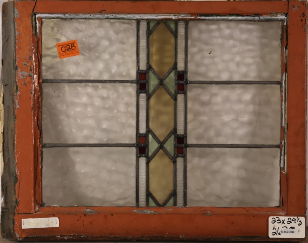 IRISH ART DECO STAINED GLASS PANEL: Irish Art Deco stained glass panel with amber, red, and green geometric detail. Approximate dimensions: h. 23", w. 29.5" Disclaimer: This is an online court ordered bankruptcy sale. Participating bidd