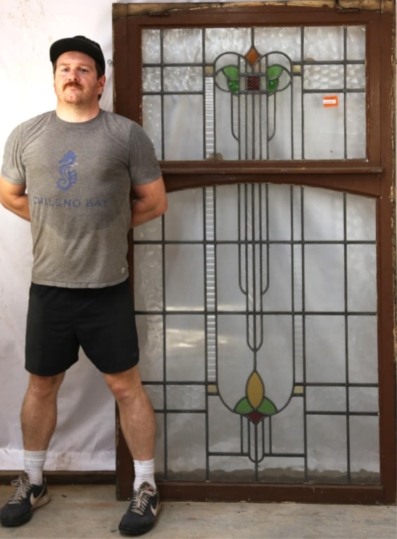 IRISH ART DECO STAINED GLASS PANEL: Irish Art Deco stained glass panel with geometric medallion in yellow, amber, red, and green, with colorless leaded glass panels, some textured. Approximate dimensions: h. 72", w. 41" Disclaimer: This