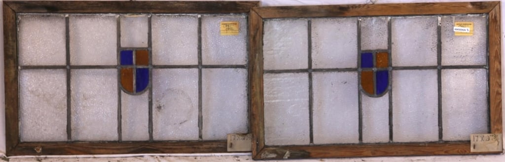 PAIR OF IRISH STAINED GLASS PANELS: Pair of Irish stained glass panels with shield-form medallions in amber and blue, set within colorless leaded glass panels. Approximate dimensions: h. 17", w. 27.5" Disclaimer: This is an online court