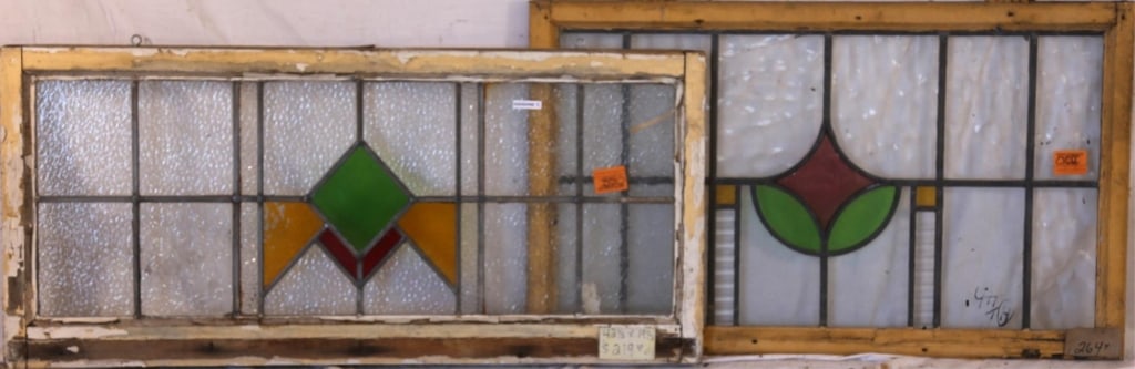 TWO ENGLISH STAINED GLASS PANELS: Two English stained glass panels with abstract geometric medallions in red, yellow, and green, set within colorless textured leaded glass panels. Approximate dimensions: h. 19.5", w. 42.5" Disclaimer: