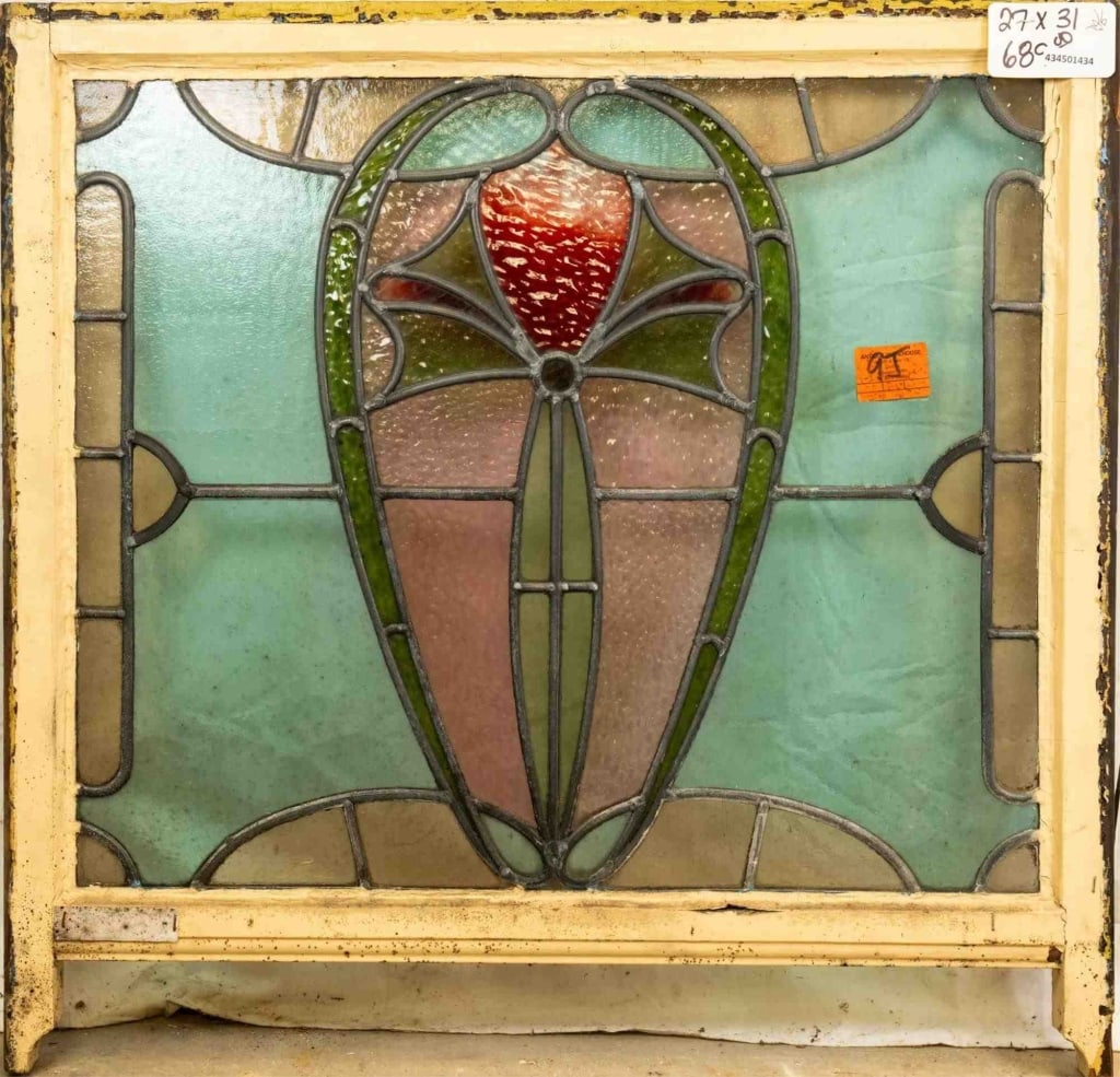FRENCH ART NOUVEAU STAINED GLASS PANEL: French Art Nouveau stained glass panel with a heart-shaped medallion, green bow motif, and wispy red glass accent. Approximate dimensions: h. 27", w. 31" Disclaimer: This is an online court ordered ba
