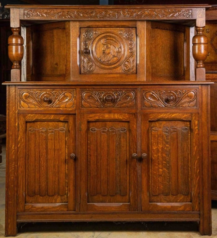 FRENCH OAK COURT CUPBOARD: French oak court cupboard with figural carved inset panels, wood-turned pulls, carved supports, and floral motif carving throughout. Approximate dimensions: h. 55", w. 50", d. 19" Disclaimer: This is 