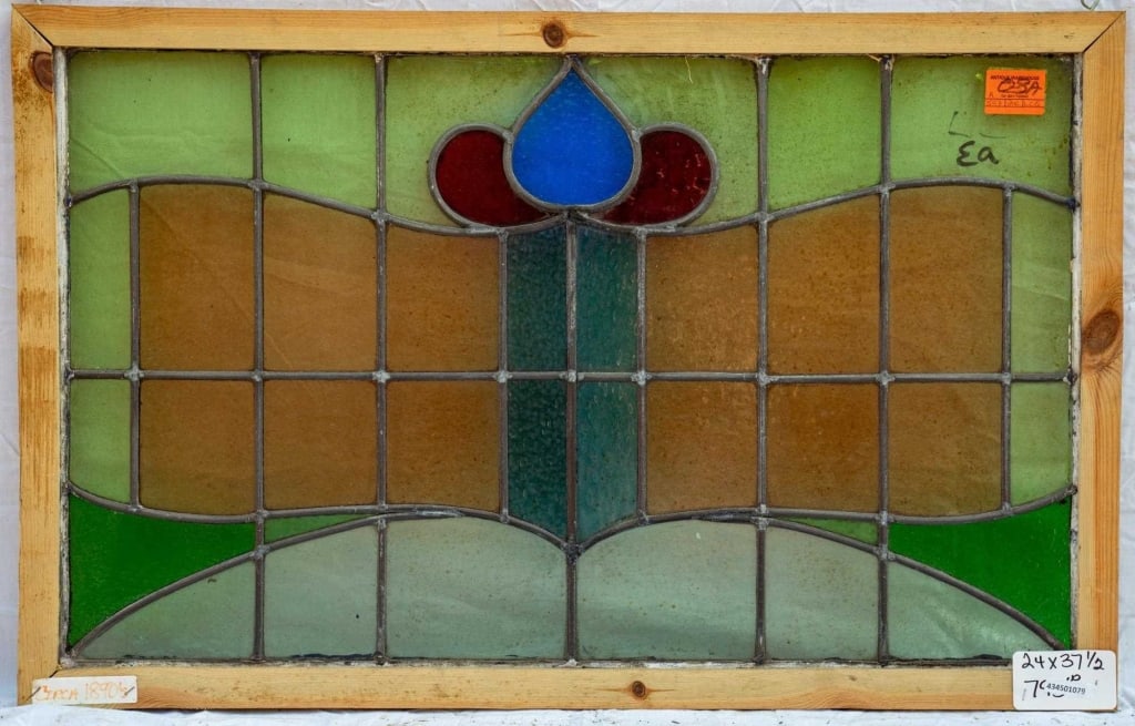 FRENCH ART NOUVEAU STAINED GLASS PANEL: French Art Nouveau stained glass panel with a red and blue flower medallion set within green and amber leaded glass panels. Approximate dimensions: h. 24", w. 37.5" Disclaimer: This is an online court
