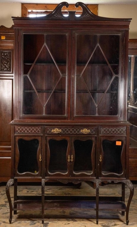 ENGLISH MAHOGANY VITRINE BOOKCASE: English mahogany vitrine bookcase with cabriole legs and carved knees, broken arch pediment, and inset carved panels. Approximate dimensions: h. 87", w. 88", d. 15" Disclaimer: This is an online court