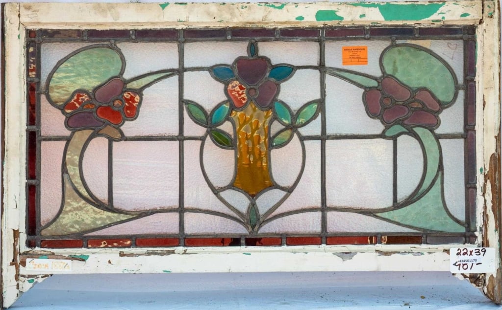 FRENCH ART NOUVEAU STAINED GLASS PANEL: French Art Nouveau stained glass panel with a central floral medallion and two symmetrical red floral accents to the sides. Approximate dimensions: h. 22", w. 39" Disclaimer: This is an online court o