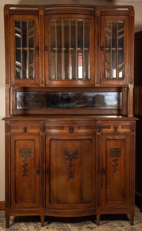 FRENCH ART NOUVEAU VITRINE BUFFET: French Art Nouveau vitrine buffet with beveled mirror, floral appliqués, teardrop pulls, and beveled and leaded glass cabinets. Approximate dimensions: h. 85", w. 54", d. 24" Disclaimer: This is an o