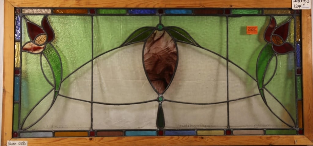 FRENCH ART NOUVEAU STAINED GLASS PANEL: French Art Nouveau stained glass panel with floral medallion, wispy glass detail, and red and green floral accents to the corners. Approximate dimensions: h. 26.5", w. 55.5" Disclaimer: This is an onl