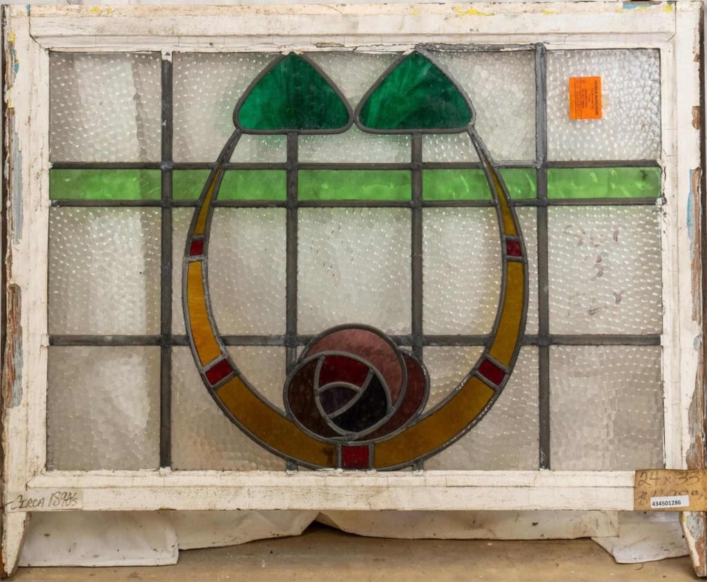 FRENCH ART NOUVEAU STAINED GLASS PANEL: French Art Nouveau stained glass panel with a floral medallion, amber garland, and green wispy glass leaf details. Approximate dimensions: h. 24", w. 33" Disclaimer: This is an online court ordered ba