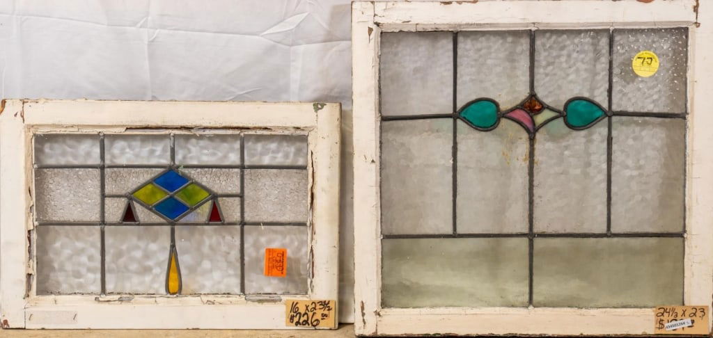 TWO CONTINENTAL STAINED GLASS PANELS: Two Continental stained glass panels, one with a floral abstract medallion and the other with a geometric medallion. Approximate dimensions: h. 24.5", w. 23" Disclaimer: This is an online court ordere