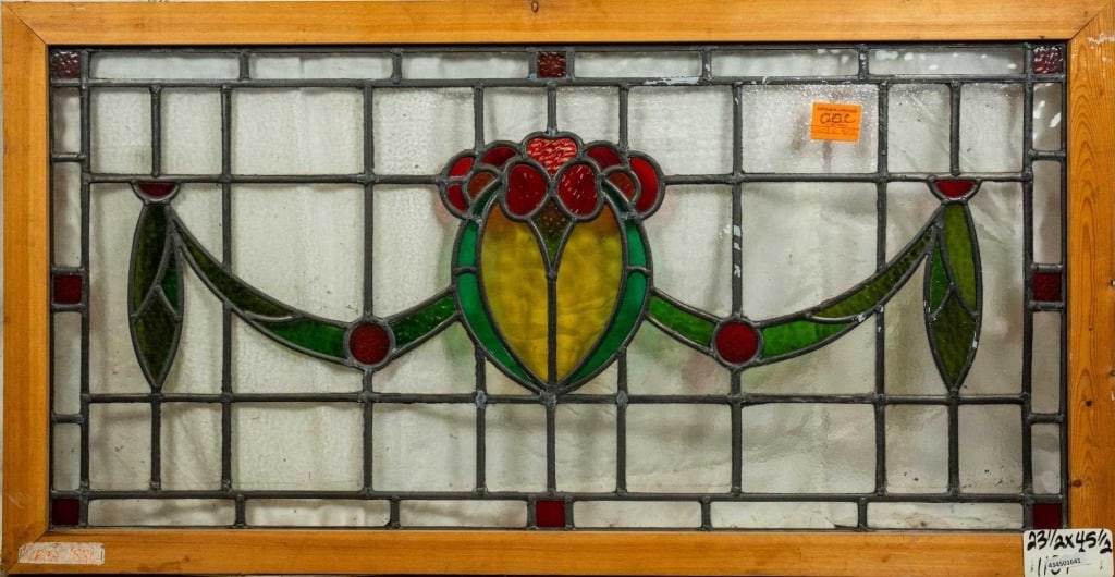 FRENCH ART NOUVEAU STAINED GLASS PANEL: French Art Nouveau stained glass panel with floral medallion, leaf motif garland details, and red stained glass accents. Approximate dimensions: h. 23.5", w. 45.5" Disclaimer: This is an online court