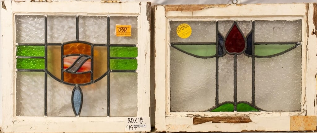 TWO CONTINENTAL STAINED GLASS PANELS: Two Continental stained glass panels, one with a shield-shaped medallion and wispy red glass accent, the other with a floral medallion. Approximate dimensions: h. 18", w. 20" Disclaimer: This is an on