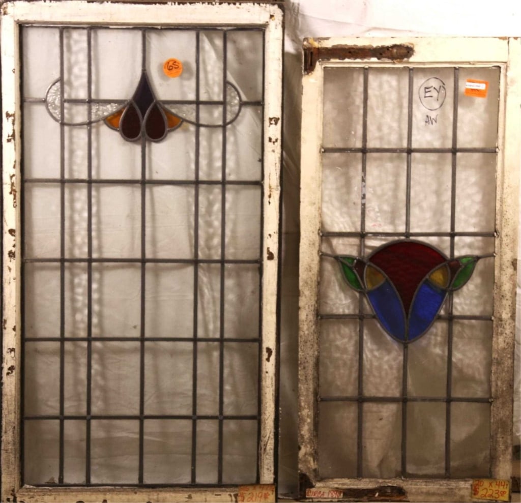 TWO ANTIQUE CONTINENTAL STAINED GLASS PANELS: Two antique Continental stained glass panels, one with a purple, red and amber medallion accented by textured colorless glass, the other with a floral motif. Approximate dimensions: h. 47.5", w. 26" D