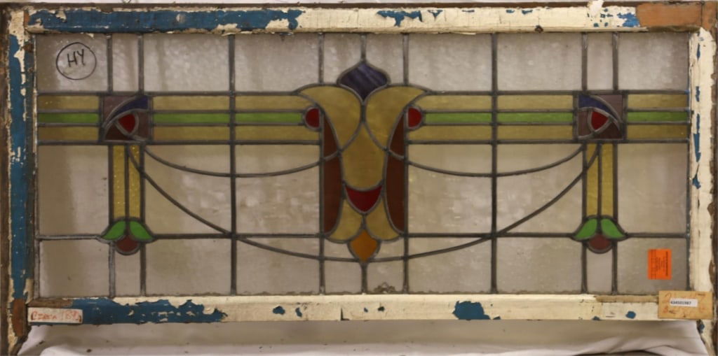 ANTIQUE ENGLISH STAINED GLASS PANEL: Antique English stained glass panel with multicolored central medallion and symmetrical floral motif side details. Approximate dimensions: h. 21", w. 47" Disclaimer: This is an online court ordered ba