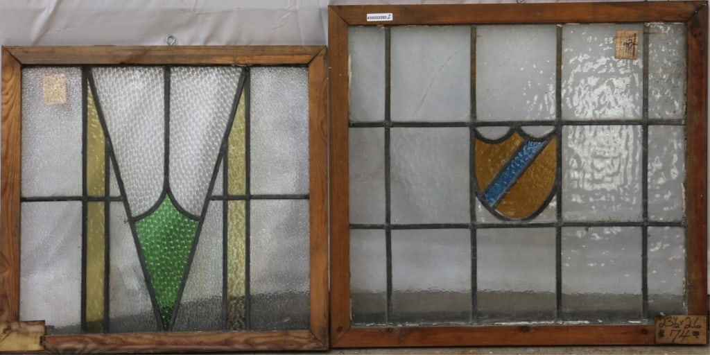 TWO ANTIQUE ENGLISH STAINED GLASS PANELS: Two antique English stained glass panels, one with Art Deco geometrical elements, another with a yellow shield-form medallion with blue accent stripe. Approximate dimensions: h. 23.5", w. 26" Disclaim
