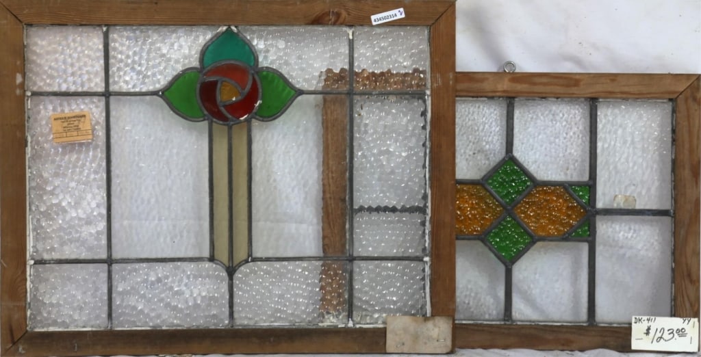 TWO CONTINENTAL STAINED GLASS PANELS: Two Continental stained glass panels, one with a floral medallion and the other with an amber and green geometric abstract medallion. Approximate dimensions: h. 21", w. 26" Disclaimer: This is an onli